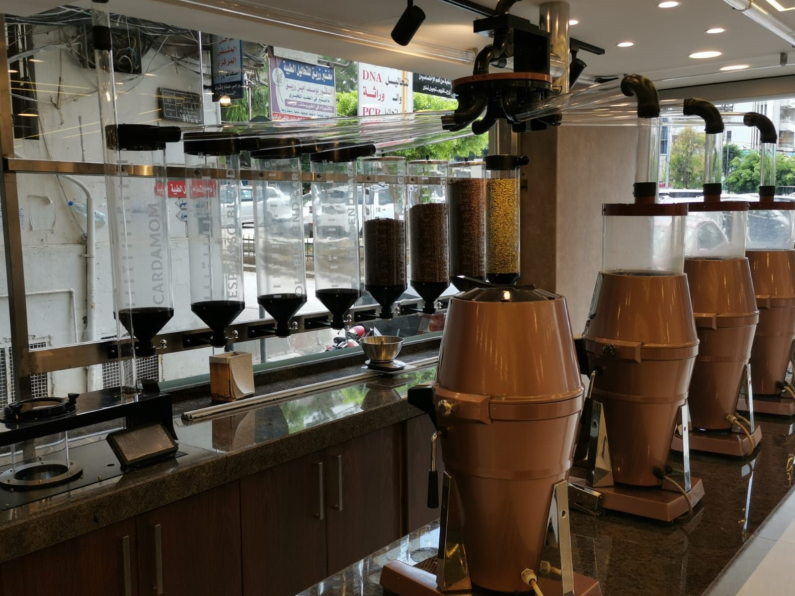 Overhead distributor and plexi pipes feeding copper grinders in a working coffee shop